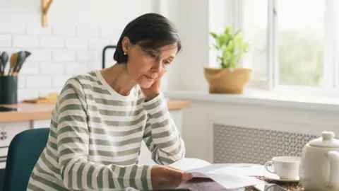 Getty Images Woman reads energy bill at kitchen table