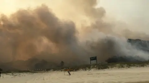 QUEENSLAND AMBULANCE SERVICE Smoke from a massive bushfire on Fraser Island seen at Cathedral Beach on 6 December 2020