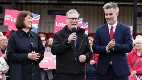 PA Media Labour Party leader Sir Keir Starmer (centre) and shadow chancellor Rachel Reeves, celebrate with David Skaith at Northallerton Town Football Club, North Yorkshire, after he won the York and North Yorkshire mayoral election