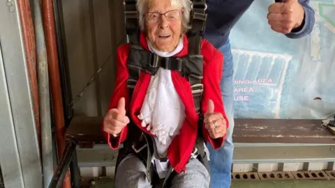 Goldster Manette Baillie practicing being in a parachute brace prior to her jump