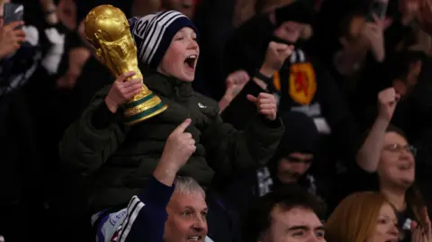 Reuters A young Scotland fan holding a replica World Cup trophy celebrates with other supports Scotland's 4-2 win over Denmark at Hampden.