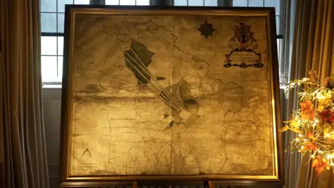 A gold-coloured map of the Blickling estate and parish on display in front of a window at Blickling Hall 