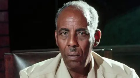 Siad Barre in a safari suit staring at the camera.