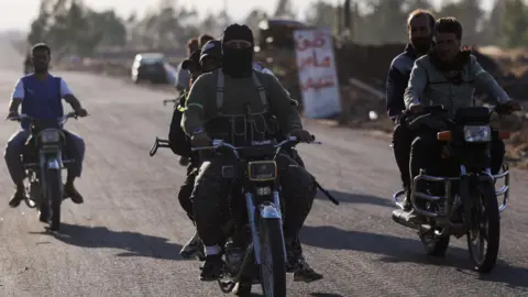 Armed Bedouin fighters ride motorbikes in southern Syria (17 July 2025)