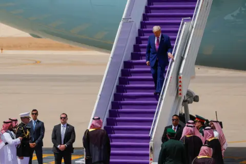 Trump walking down the step of a plane
