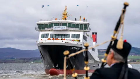 A piper plays on the banks of the Firth of Clyde with the newly-launched Glen Rosa ferry in the background. 