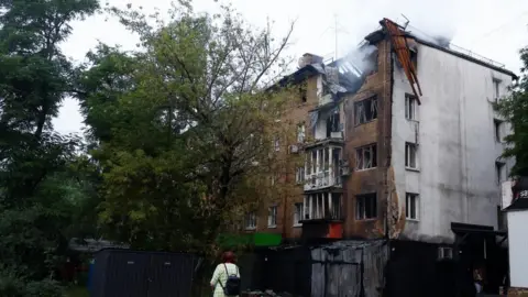 A woman looks at a residential building in Kyiv damaged in a Russian drone attack. Photo: 10 July 2025
