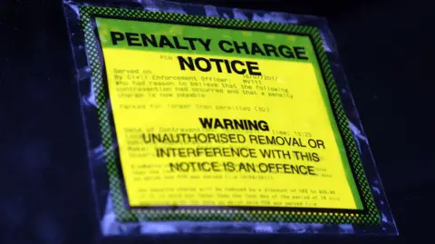 Stock shot of a penalty notice sticker, it's yellow and is stuck to the windscreen.