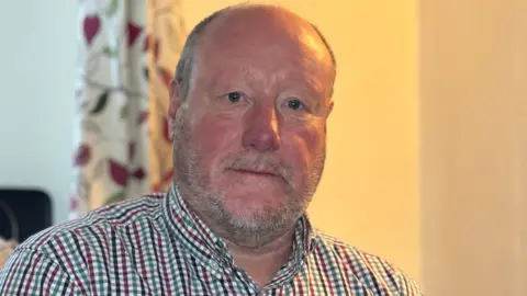 Kevan Ball during the BBC interview. He is in a room and looking at the camera.