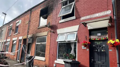 Outside of a house in Lancaster Street, Leicester, that has been damaged by a fire. Smoke damage to the front door and first floor window of the terrace property. A fire tape cordon is in place.