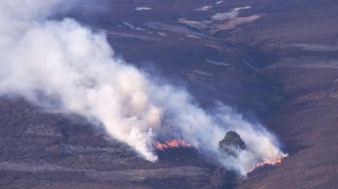A wildfire takes hold on the hillside