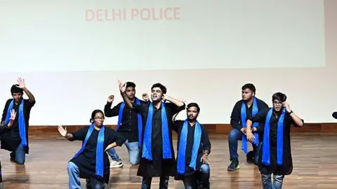 Getty Images artists, wearing black jackets and blue swings, perform a performance to increase the awareness against cyber -damping, organized by the Delhi police in the Lotus Temple, July 26, 2025 in New Delhi, India. 
