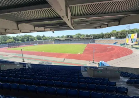 A high view of Crystal Palace National Sports Centre from the top of a stand, with the track and other stands laid out below.