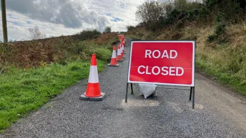 Phil Bodmer/ BBC Road closed sign on landslip-hit road