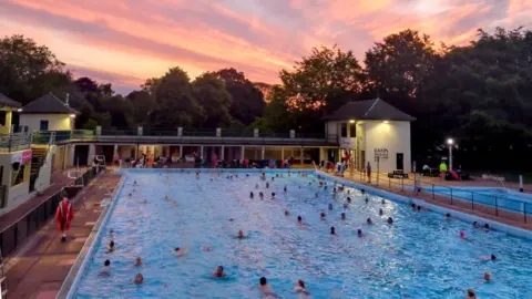 Clare Marshall  Summer Solstice swim at Peterborough Lido with a pink sunrise in the background