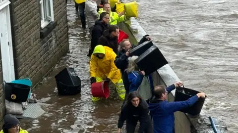 People bail out water with buckets on a flood-hit street