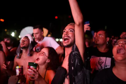 People watching lady Gaga concert, with mouths open, smiling 
