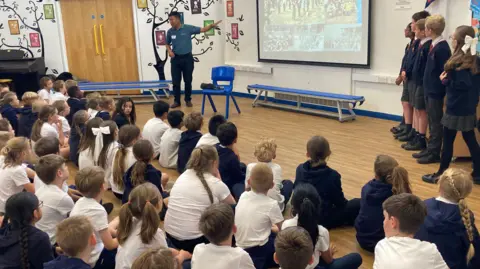 Dawa Geljen Sherpa is pictured talking to the children in a school hall, showing them pictures of Nepal on a big screen.