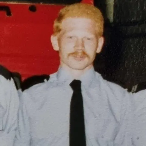 Steve Paige An old photo of Steve, who has a handlebar moustache and ginger hair. He is wearing a light blue shirt with a black tie.