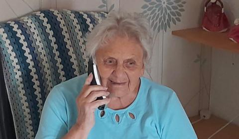 An elderly woman making a phone call at home.