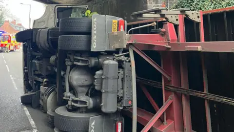 Birmingham New Street The lorry lies on its side under the bridge with emergency vehicles parked nearby