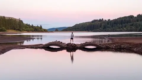 Getty Images Stone bridge at the Llwyn-Onn Reservoir in Merthyr Tydfil in 2026. The bridge is visible above the water. A boy is standing on it