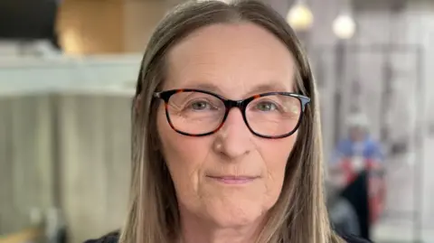 BBC/Spencer Stokes Lisa Hanson with long hair and wearing black glasses
