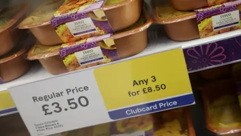Reuters Chicken tikka masala ready meals on a shelf next to a sign offering discount deals inside a Tesco supermarket in Manchester.