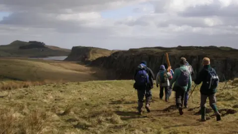 Northern Cross A group of walkers head towards a stretch of Hadrian's Wall 