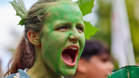 EPA Headshot av en demonstrant med ansiktet målat grönt på ett klimatrally