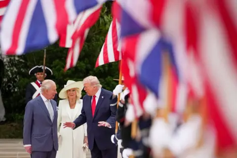 Getty Images The King, Queen and Trump walk outside the White House with UK and US flags in the foreground.