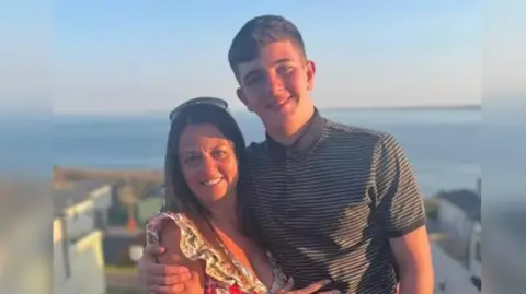 Cole Cooper and Wendy Stewart with arms around in each other and the ocean in the background