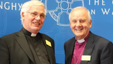 Philip Morris/The Church in Wales Archdeacon Philip Morris with former Archbishop of Wales Barry Morgan, both dressed in clerical garb and smiling at the camera 