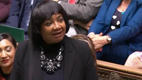  UK Parliament/PA Ms Abbott is wearing a black jacket and a black necklace. She's in parliament.