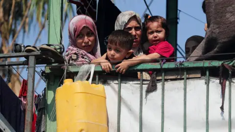Palestinians look on at the site of an overnight Israeli strike on a school sheltering displaced families, in Gaza City