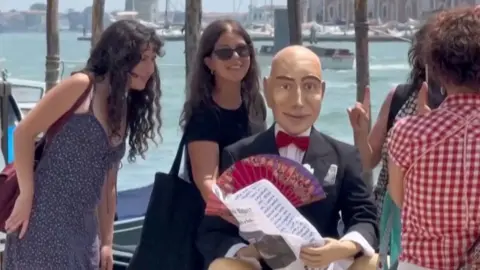 People pose for a photo with a Jeff Bezos mannequin