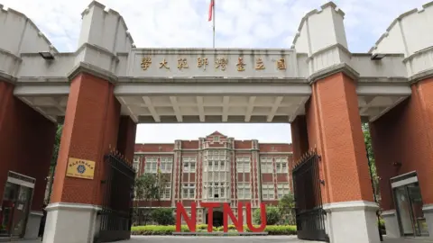 National Taiwan Normal University The front of the university, showing a grand, red and white brick building, with large letters in the garden that spell out 'NTNU'