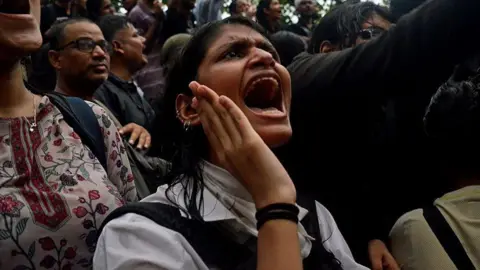 A crowd gathered at Delhi's Jantar Mantar in solidarity with the Cockroach Janata Party, demanding educational reforms and India's education minister Dharmendra Pradhan's resignation on 22 July. A woman protester wearing a white shirt participates in sloganeering.