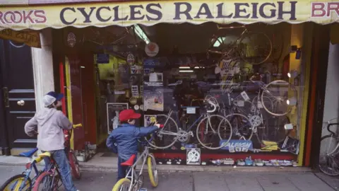 Getty Images Two boys on bikes looking through the window of a Raleigh shop in Paris in 1983