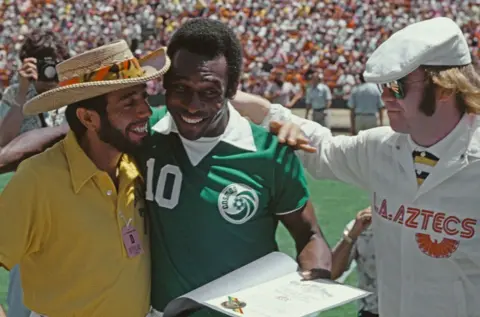 Getty Images Sérgio Mendes woont samen met Pelé en Elton John een LA Aztecs-wedstrijd bij in Los Angeles, 1977.