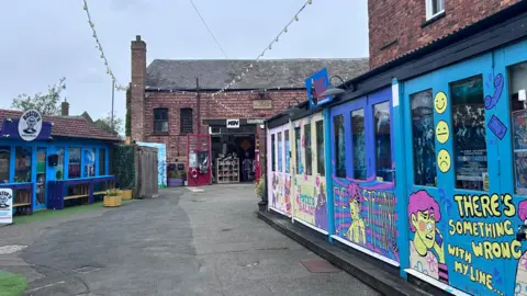 Kate Bradbrook/BBC An external view of the Yards in Kettering. The shops are brightly coloured with street art.