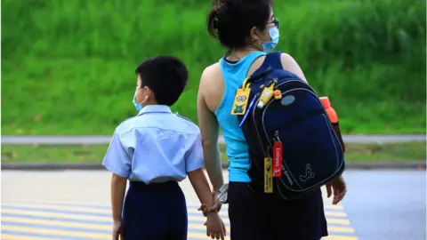 Getty Images A woman walks a child to school donning the protective mask