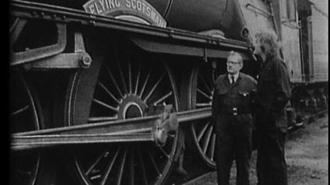 Peter Purves looks on at the Flying Scotsman next to its driver.