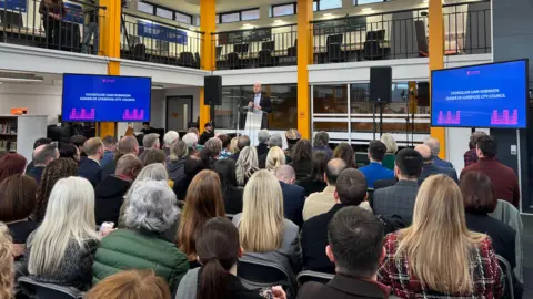 BBC/Claire Hamilton People sit and listen to a speech at Spellow Library during its reopening