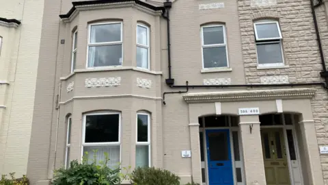 GUY CAMPBELL/BBC Grey brick facade of two storey building called Harmony House 