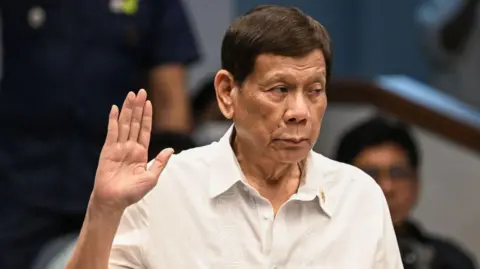 Getty Images Former Philippine president Rodrigo Duterte takes an oath as he attends a senate probe on the drug war during his administration