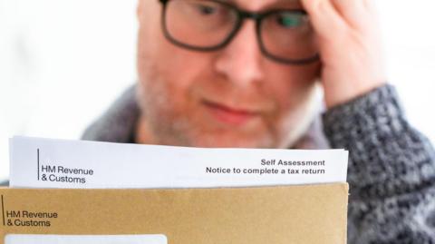 Man with glasses looking at letter from HMRC 