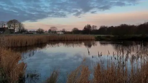 Lucyl Harrison The former duck pond full of water in Hempton. The picture has been taken at sunset and the colours of the sky are reflected on the water.