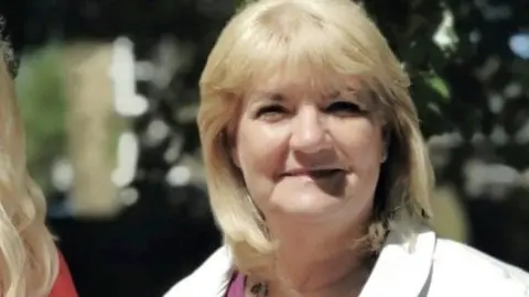 National Lottery Wendy Hope has blonde hair a violet shirt and white jacket