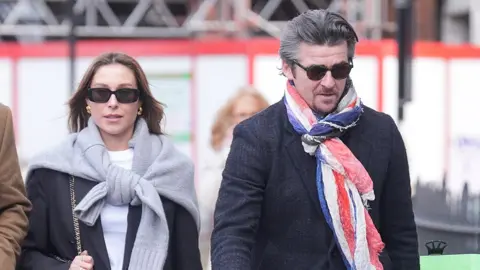 Georgia and Joey Barton both walk while wearing sunglasses and scarves outside Westminster Magistrates' Court on 24 January